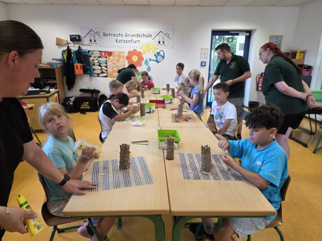 Kinder beim Basteln von Nisthilfen aus Bambusrohr im Ferienprogramm der Betreuten Grundschule Katzenfurt
