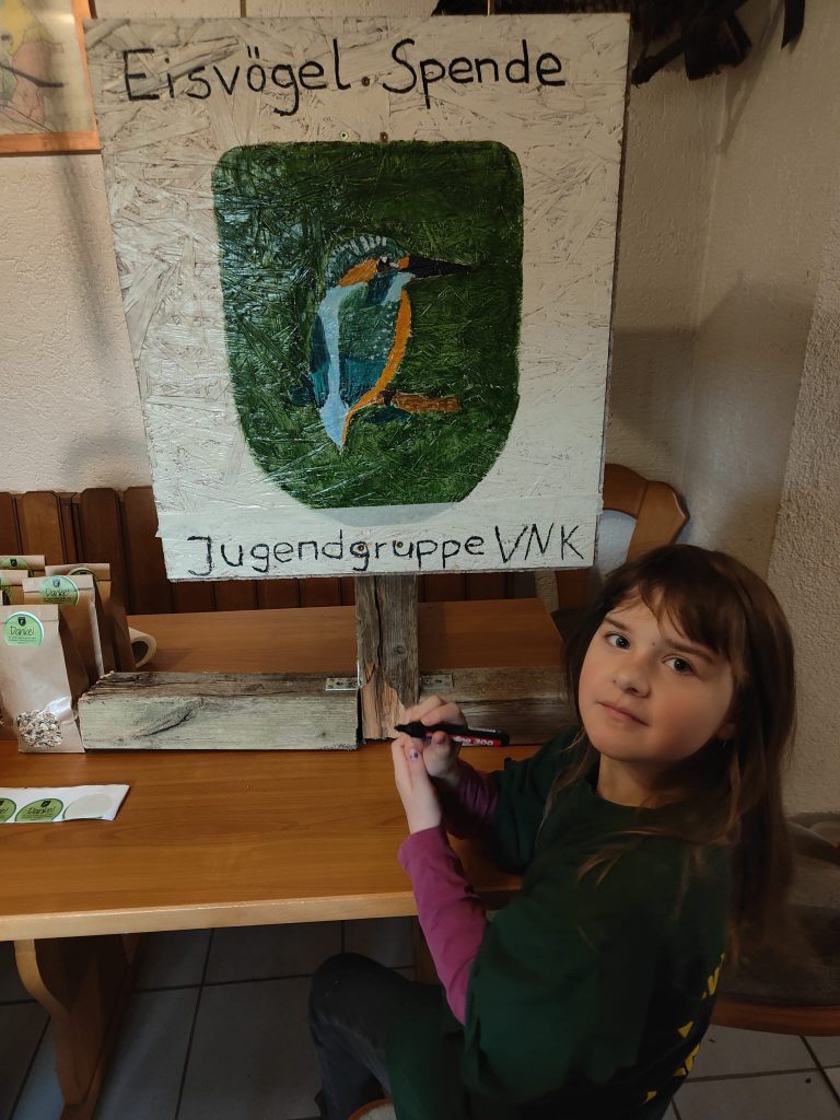 Eisvögel versiegeln das Logo der Spendenbox mit Klarlack