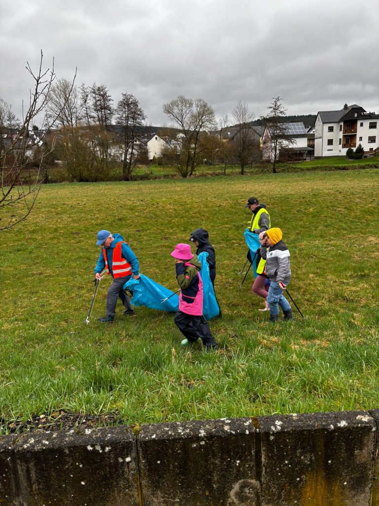 Kinder sammeln Müll beim Naturschutz an der Dill im Regen