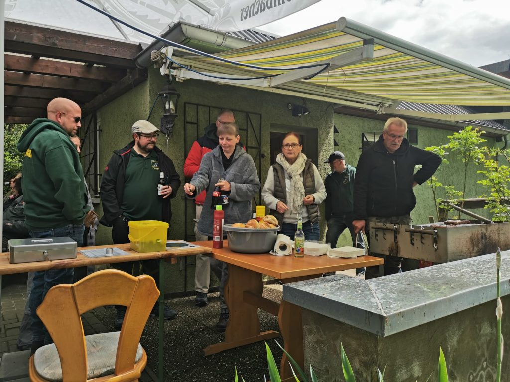 Gäste genießen Bratwurst beim regnerischen Vatertagsfrühschoppen auf dem Vereinsgelände