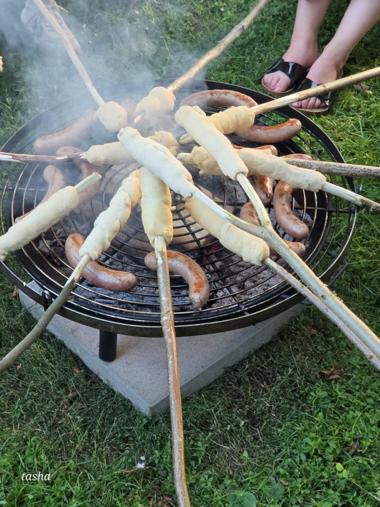 Kinder backen Stockbrot am Lagerfeuer während des Naturcamp